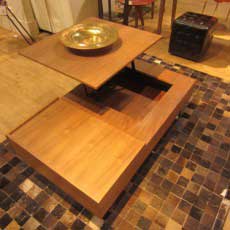 Walnut wood coffee table that has a hinge to allow the top to swivel upward to form a higher table. Transforming furniture.