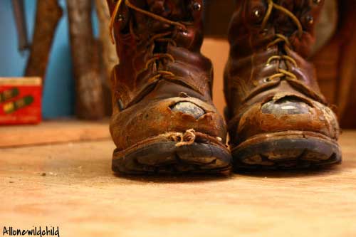 well worn steel toed boots with the steel showing through the toes.