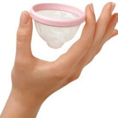 A woman's hand delicately holds a flexible pink plastic cup between her index and forefinger.