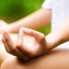 Contentment. A woman's hand is resting on her knee, with her index finger and thumb touching, depicting the calm and peace of meditation.