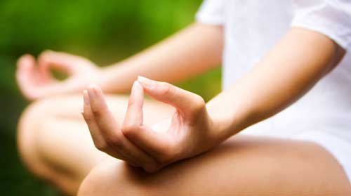 Contentment. A woman's hand is resting on her knee, with her index finger and thumb touching, depicting the calm and peace of meditation.