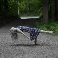 A woman wearing a dress appears to be floating while lying on her back with only one toe on the ground.