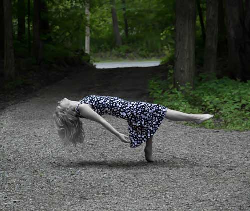 A woman wearing a dress appears to be floating while lying on her back with only one toe on the ground.