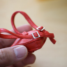 A tiny red leather backpack which is about the size of a human thumb.