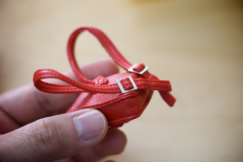 A tiny red leather backpack which is about the size of a human thumb.