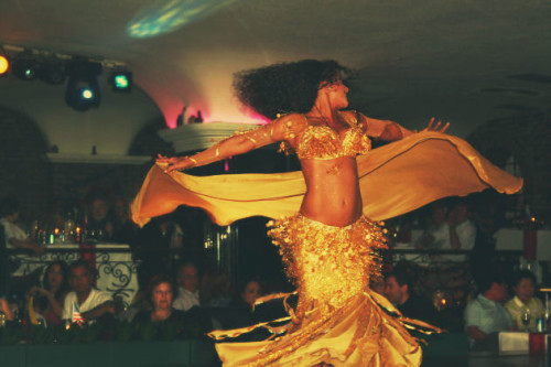 A bellydancer in gold swirls dramatically to the amazement of the audience, with the luxury of space.