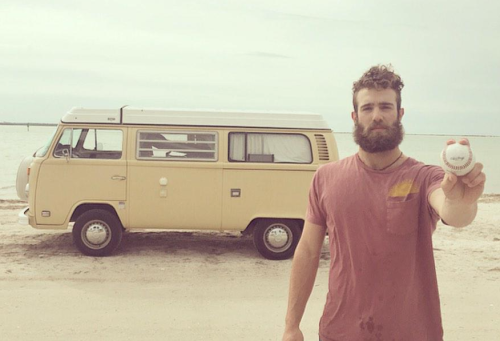 The simple life. Millionaire pitcher Daniel Norris holds a baseball out while standing on the beach in front of the VW van he lives in.