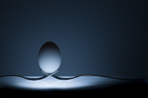 Life lessons are often about balance. An egg perfectly balances on two interlaced forks, sitting on an underlit table.