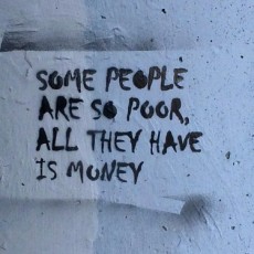 A message, spray painted on a concrete wall, "Some people are so poor, all they have is money"