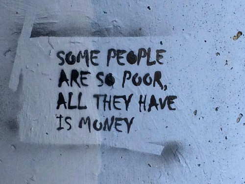 A message, spray painted on a concrete wall, "Some people are so poor, all they have is money"